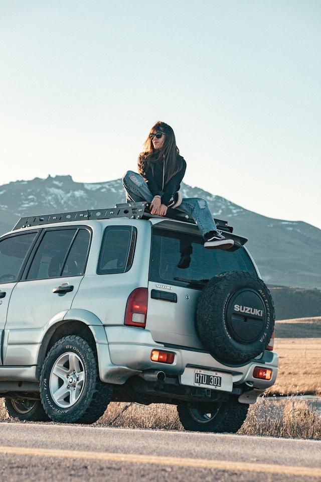 Image of a Suzuki Vitara with a Lady sat on the roof